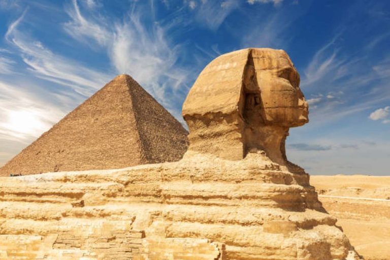 An ancient pyramid and the Great Sphinx of Giza stand in the desert sand.